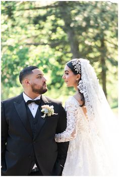 a bride and groom standing together in front of trees