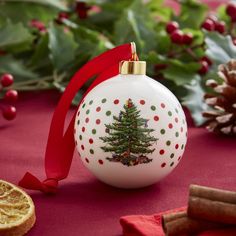 an ornament with a christmas tree on it next to orange slices and holly