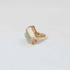 a gold ring with white and blue stones on it's sides, sitting on a white surface