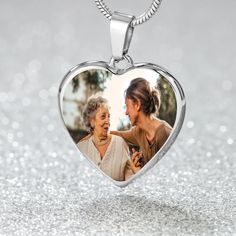 a heart shaped pendant with an image of two women in it on a silver background