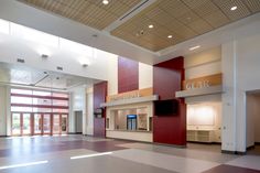 an empty room with red and yellow walls, white floors and large windows on the ceiling