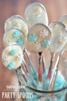 some cake pops are in a glass vase with blue flowers on them and white frosting