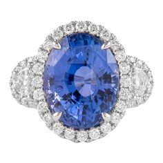 an oval blue and white sapphire ring with diamond shoulders, surrounded by two smaller round diamonds