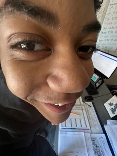 a close up of a person's face with papers on the desk in the background