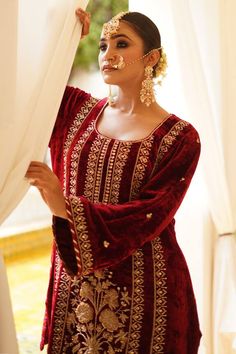 Maroon straight kurta with gold zardosi, aari and kundan embroidery. Paired with a gharara and dupatta.
Components: 3
Pattern: Embroidered
Type Of Work: Zardosi, Aari, Kundan
Neckline: U Neck
Sleeve Type: Flared
Fabric: Kurta: Silk Velvet, Gharara: Satin Silk, Dupatta: Organza
Color: Maroon
Other Details: 
Approx. product weight: 1.5 kg
Length:
Kurta: 33 inches
Gharara: 38 inches
Note: Outfit worn by the model on the right is not for sale.
Occasion: Mehendi and Haldi - Aza Fashions Nida Sharara With Traditional Drape For Reception, Reception Sharara With Zari Work In Nida, Reception Nida Sharara With Zari Work, Nida Sharara With Zari Work For Reception, Nida Sharara For Reception And Festivals, Designer Nida Sharara With Pallu, Dabka Embellished Sharara For Diwali Reception, Designer Nida Sharara For Diwali, Festival Nida Sharara For Reception