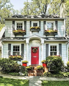 a white house with red front door and window boxes on the windows sills