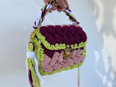 a hand holding a multicolored purse with tassels