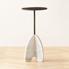 a white surfboard shaped table with a black top on a wooden floor in front of a wall