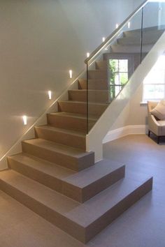 an empty room with some stairs and lights on the wall next to the couches