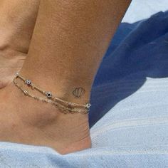 a woman's foot with a tattoo on it and a chain around the ankle