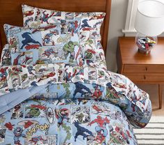 a bed covered in comic themed sheets and pillows