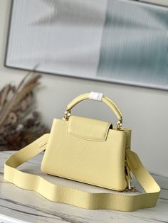 yellow small This small Capucines handbag is made of Taurillon leather, and the metal and resin links are interlocked with each other. In addition to the top handle and detachable wide shoulder strap, it adds a fun carrying method. The signature flap of the Capucines collection is folded in to reveal the logo. 

Dimensions: 27 x 18 x 9 cm Modern Yellow Satchel With Gold-tone Hardware, Evening Yellow Satchel With Double Handle, Yellow Evening Satchel With Double Handle, Evening Yellow Double Handle Satchel, Luxury Yellow Bag With Top Carry Handle, Luxury Yellow Satchel For Evening, Luxury Top Handle Satchel, Elegant Yellow Satchel With Top Carry Handle, Yellow Satchel With Adjustable Strap For Evening