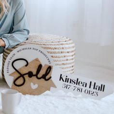 a woman sitting on the floor next to a ball of twine and a sign that says sold