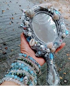 a person holding up a mirror with beads on it