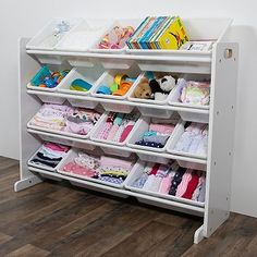 a white shelf filled with lots of children's clothing and toys on top of wooden floors