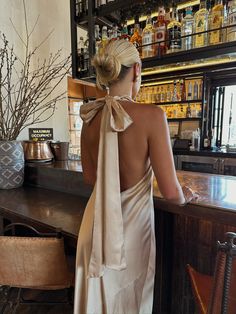 a woman in a dress standing at a bar with her back turned to the camera