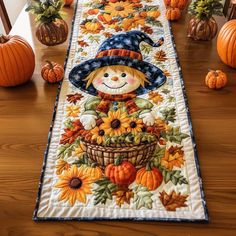 a table runner with a scarecrow and sunflowers on it, surrounded by pumpkins