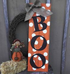 a wooden sign with the word boo on it next to a scarecrow and pumpkin