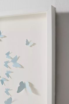 a white frame with paper cut butterflies in the shape of birds flying through the sky