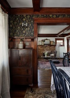 a dining room table and chairs in front of a wooden cabinet with floral wallpaper