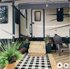 an rv is parked in the yard with potted plants next to it and a black and white checkered rug on the floor