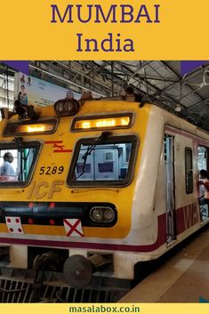 a yellow and red train sitting inside of a train station next to people standing on the platform