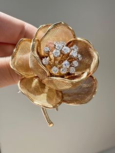 This beautiful French assayed brooch features a flower design crafted from 18K gold with mesh pedaling that can be opened and closed. It is set with sparkling white diamonds in the center that tremble in harmony. The special en tremblant technique gives the flower a subtle, graceful movement. Perfect for adding a touch of elegance to any outfit, this brooch combines classic charm with timeless beauty. Measurement: 2.3 inch by 1.55 inch  Mechanism: En Tremblant, Open Close Pedals Diamonds:  Carat Weight: 1.3 Carats Setting: Pave Cut: Round Brilliant Quality: VS1-VS2 Clarity, F-G Color Markings: French Assay Mark, "FRANCE 18KT" Metal: 18K Gold Weight: 33.0 Grams Graceful Movement, Diamond Brooch, 3 Carat, Flower Brooch, White Diamonds, A Flower, Flower Design, Diamond White, Timeless Beauty