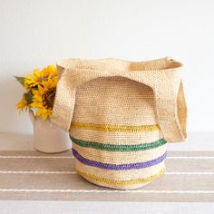 a straw bag sitting on top of a table next to a vase with sunflowers