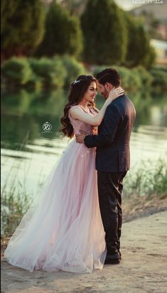 a man and woman standing next to each other near water