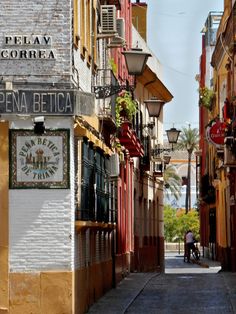 a narrow street with buildings and people walking on the sidewalk in front of it,