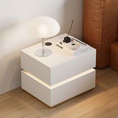 a white table with a remote control on it next to a brown chair and lamp