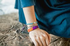 a person wearing bracelets on their wrist sitting on a table with an intricate design