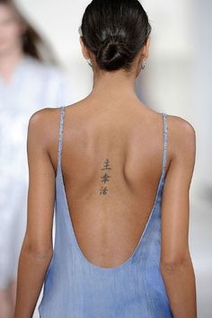 the back of a woman's dress with tattoos on her upper and lower back