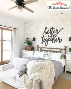 a bedroom with white brick walls and wooden bed frame, black lettering on the wall