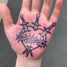 a person's hand with a tattoo on it and two swords in the middle