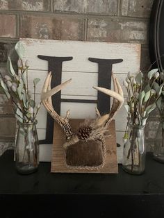 some deer antlers are sitting in vases on a table next to a brick wall