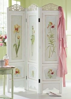 a room divider with flowers painted on it and a pink scarf hanging from the door