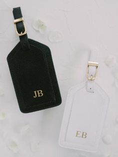 two luggage tags sitting next to each other on top of a white cloth covered surface