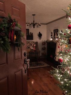 a christmas tree in the corner of a living room with lights on and wreaths hanging from it