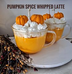 two cups filled with whipped cream and pumpkins