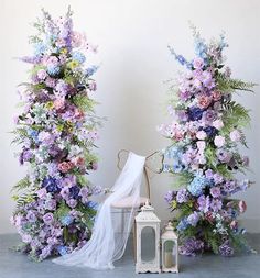 an arrangement of flowers and a white lantern on the floor next to eachother