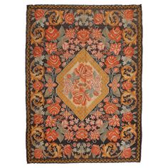 an orange and black rug with flowers on the center, surrounded by other floral designs