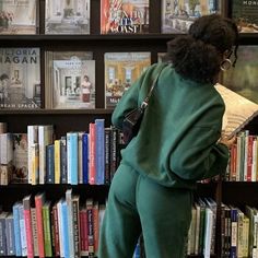 a woman reading a book in front of a bookshelf filled with many books