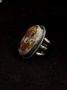 This is a Natural Mexican Fire Opal from Natural Fire Opals in Magdalena,  Jalisco Mexico. It is a natural form cabochon. Set in sterling and fine silver. It has a 15mm wide band, made with 6 gauge half round sterling wire. All unique and handmade by me with Heart & Soul! It is sz. 8.25 Please let me know if you have any questions.  Thank you for visiting! Susan  (video coming soon) Silver Opal Fusion Jewelry, Fusion Style Oval Rings With Polished Finish, Unique Untreated Ring Jewelry, Handmade Oval Opal Ring Fine Jewelry, Handmade Oval Opal Ring In Fine Jewelry Style, Silver Opal Ring With Natural Inclusions In Sterling Silver, Sterling Silver Opal Ring With Natural Inclusions, Adjustable Silver Jewelry With Natural Inclusions, Fusion Style Oval Jewelry With Polished Finish