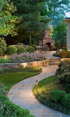 a stone path leading to a patio and dining area in the back yard is lit up with lights