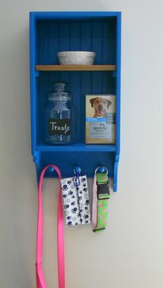 a blue shelf with some items on it and a pink leash hanging from the wall