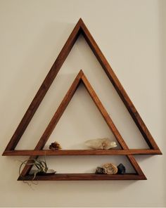 three wooden shelves with plants and rocks on them in the shape of triangulars, against a white wall