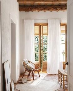 a living room with white curtains and wooden furniture