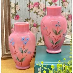 two pink vases with flowers painted on them