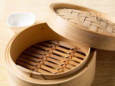 two wooden steamers sitting on top of a table next to a white bowl and spoon